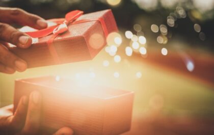 Person opening gift with magical lights glowing from it