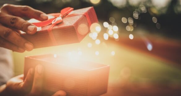 Person opening gift with magical lights glowing from it