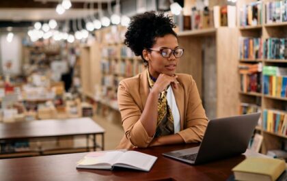 Instructor sitting in library looking at computer