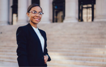 Young woman stands in front of building smiling