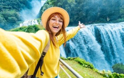 Woman taking selfie in front of waterfall