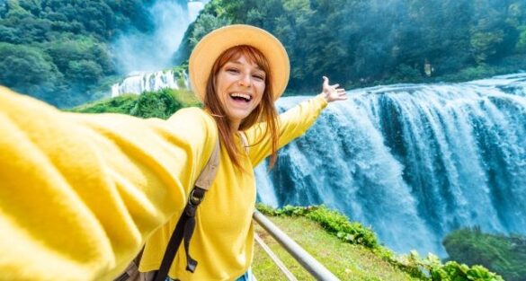 Woman taking selfie in front of waterfall