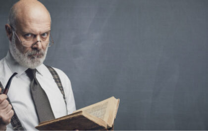 Older librarian holds book with stern face