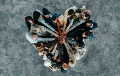 Group of people huddled together with hands in the middle