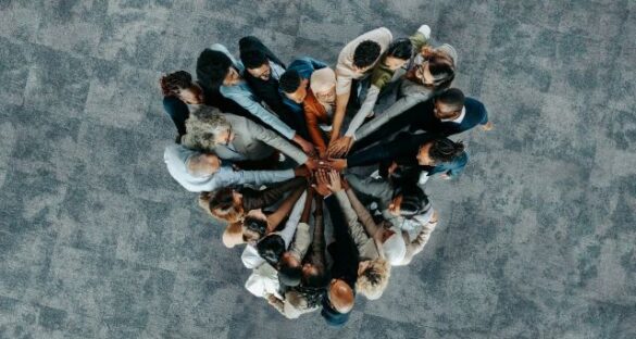 Group of people huddled together with hands in the middle