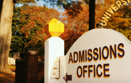 wooden-admissions-office-sign-at-college-campus-on-a-fall-day