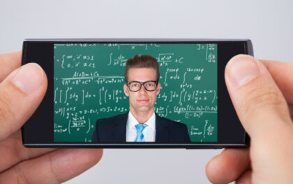 teacher-in-front-of-chalkboard-on-phone-being-held-for-online-learning