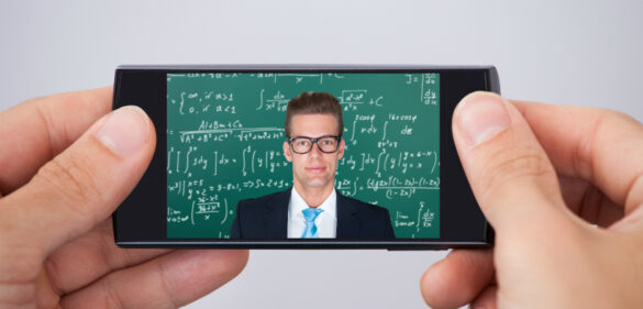 teacher-in-front-of-chalkboard-on-phone-being-held-for-online-learning