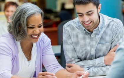 older-female-smiling-at-table-with-assorted-colleagues