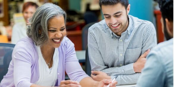 older-female-smiling-at-table-with-assorted-colleagues