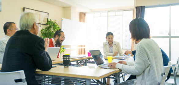 diverse-group-of-happy-people-working-in-a-room-smiling-at-a-desk-with-laptops