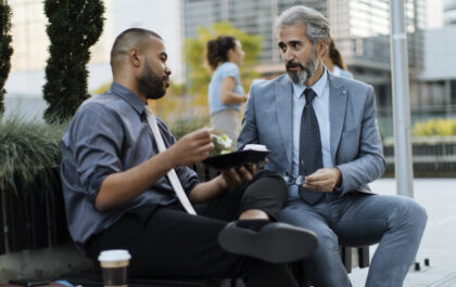 two-men-in-suits-on-park-bench-conversing-one-younger-one-older