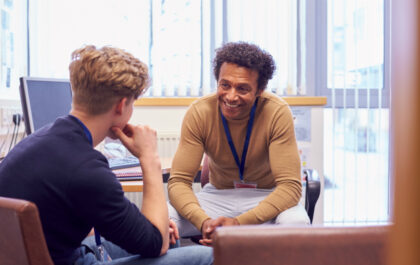 Male College Student Meeting With Campus Counselor Discussing Mental Health Issues