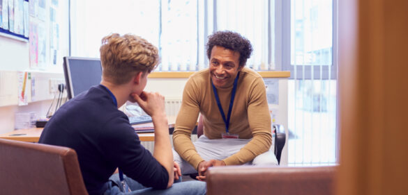 Male College Student Meeting With Campus Counselor Discussing Mental Health Issues
