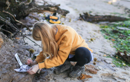 Final year female Geology student taking coastal rock samples and marking sample bags on the South of England as part of her final year Geology dissertation on sea level changes in the UK