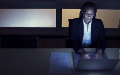business-woman-in-dark-room-at-desk-on-computer-working